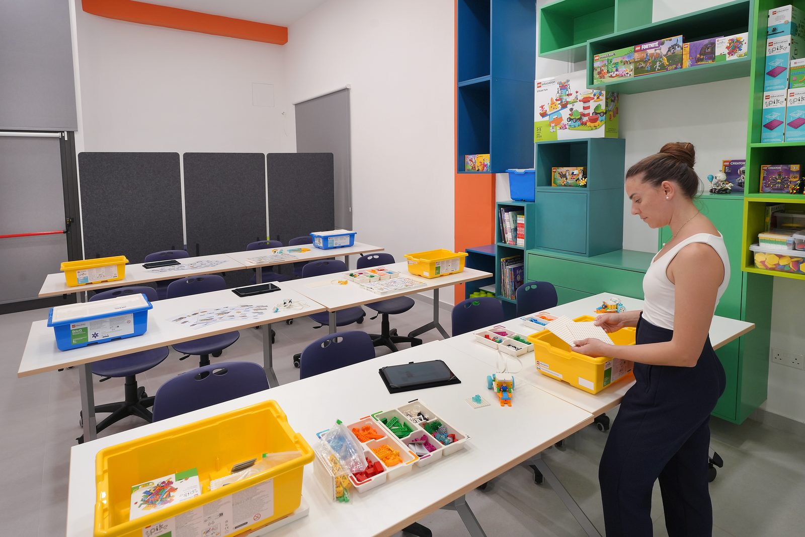 A teacher preparing LEGO Education materials at a classroom table